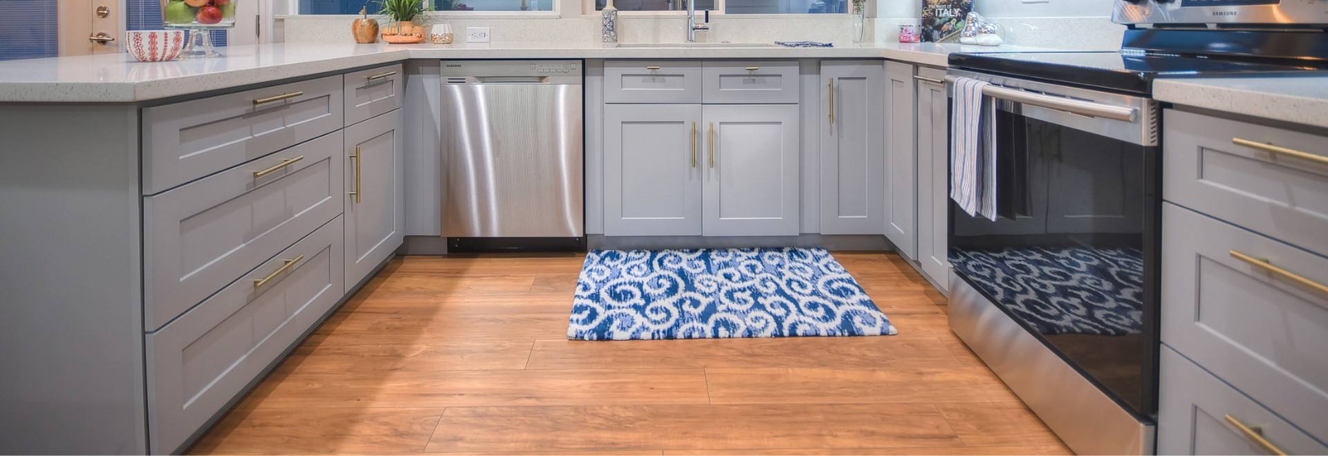 Modern kitchen with blue patterned rug and stainless steel dishwasher.