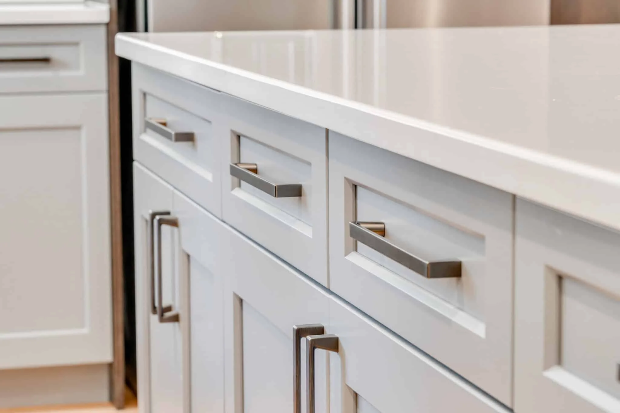 Close-up of modern kitchen cabinet handles and drawers with a white countertop.